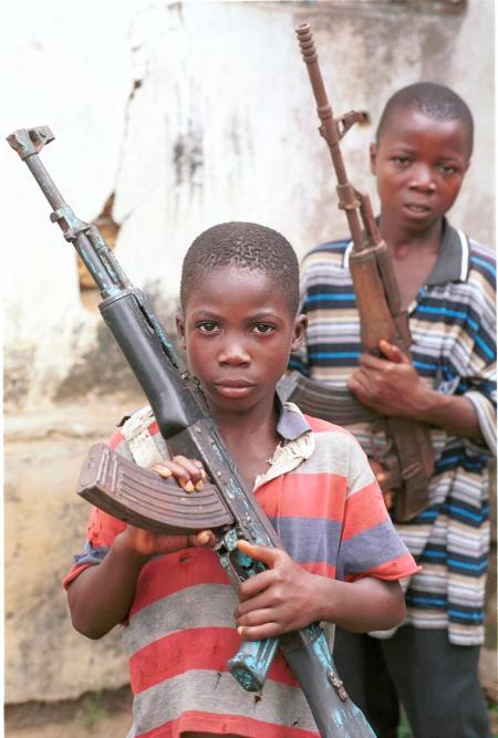 Ansu Konneh, left, with David Jallah age 15  both former LURD Child soldiers pictured in Bomi Hills, Bomi county, liberia, West Africa. Pictured with Kalashnikov AK-47 machine guns . Photograph by Colin Mearns.  16  April 2004